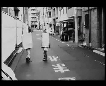 9. Tokyo Kids, 2012. 1:06 Min. Schwarz-Weiß, Sound. In den Straßen von Tokyo spielen zwei Kinder. Das eine trägt eine Maske mit einem Minus-Zeichen, das andere trägt eine Maske mit einem Plus-Zeichen. Das kindliche Spiel schwankt zwischen Zärtlichkeit und Brutalität. Es bleibt offen, ob die Kinder für die Kamera „performen“ oder ob es eine Kamerabeobachtung ist.